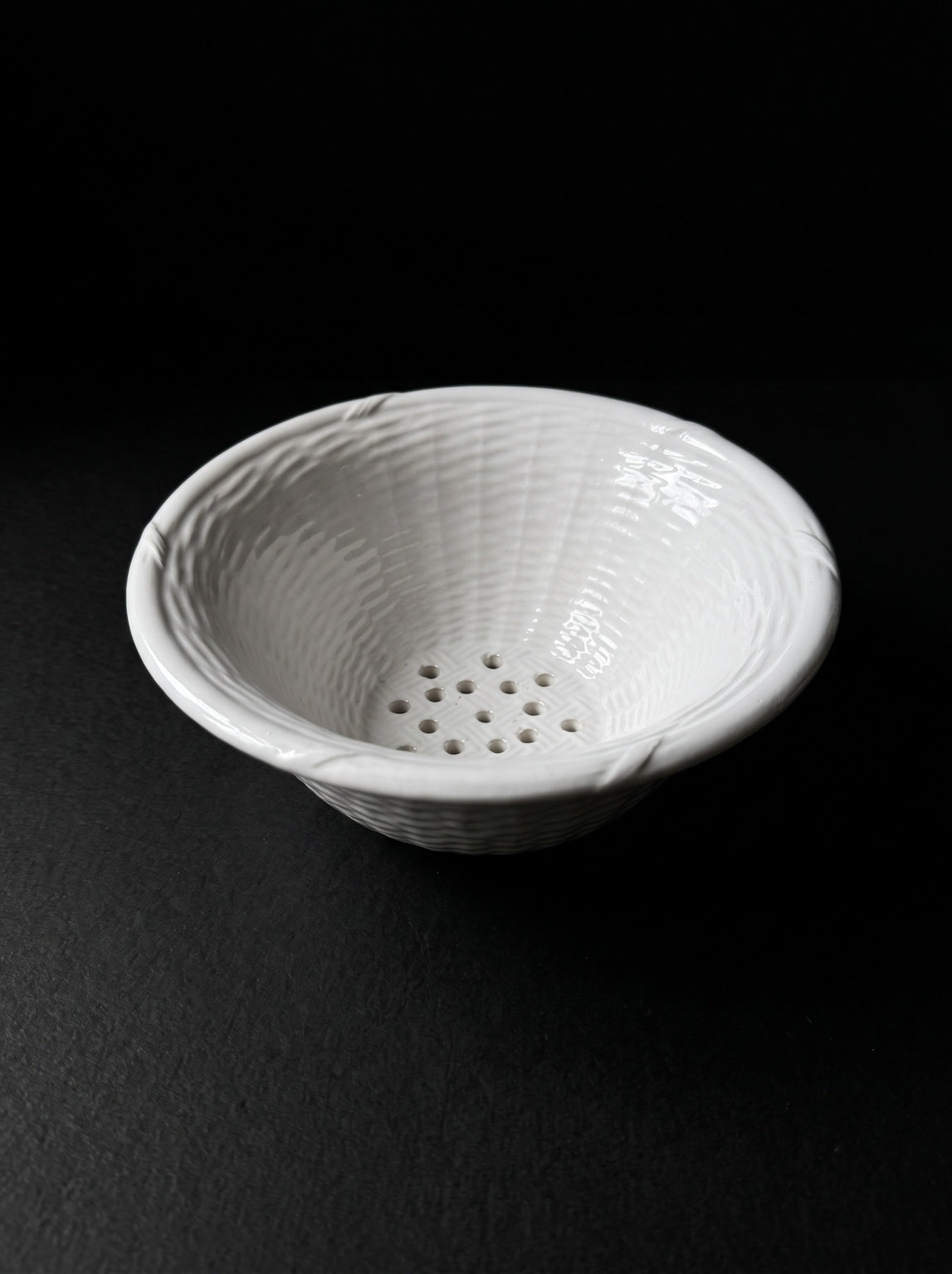 Vintage white ceramic colander on dark background