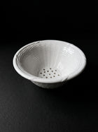 Vintage white ceramic colander on dark background