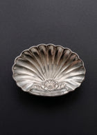 Vintage sculptural silver-toned shell soap dish photographed against a dark background