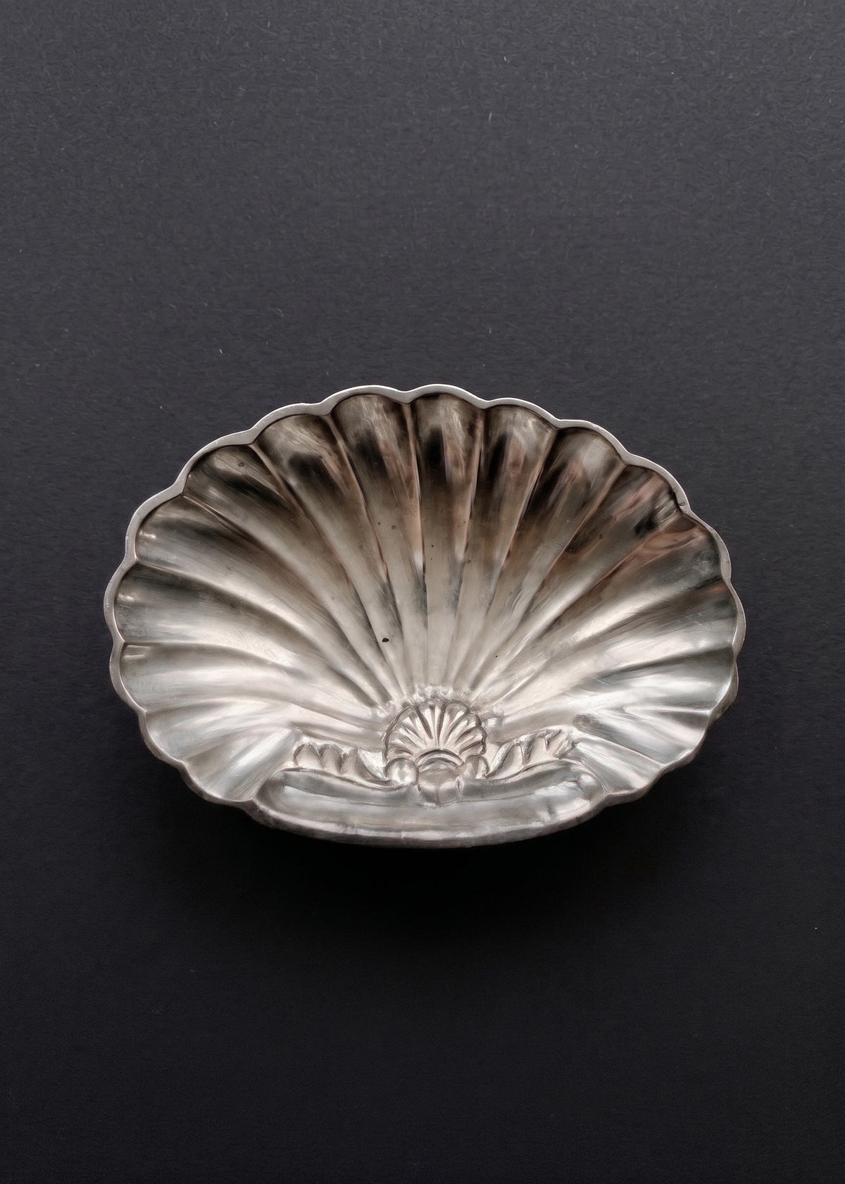 Vintage sculptural silver-toned shell soap dish photographed against a dark background