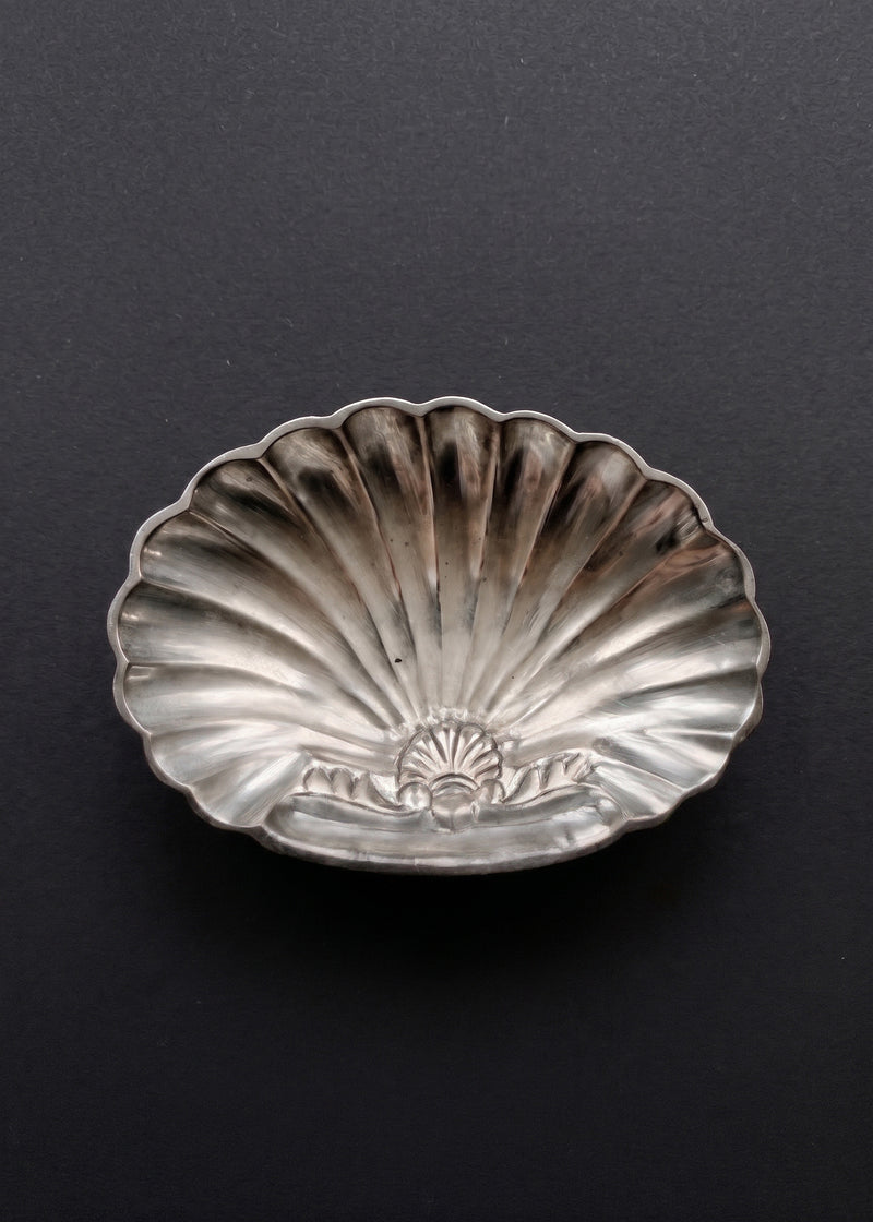 Vintage sculptural silver-toned shell soap dish photographed against a dark background
