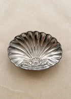Vintage silver-toned shell-shaped soap dish with natural patina on warm neutral background