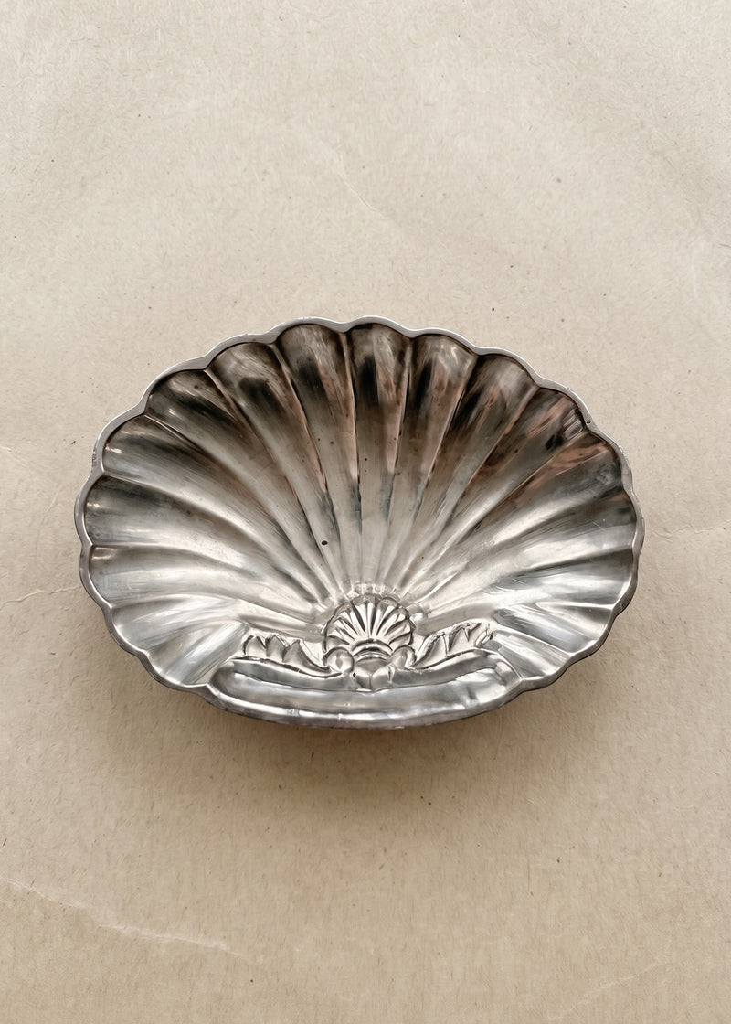 Vintage silver-toned shell-shaped soap dish with natural patina on warm neutral background