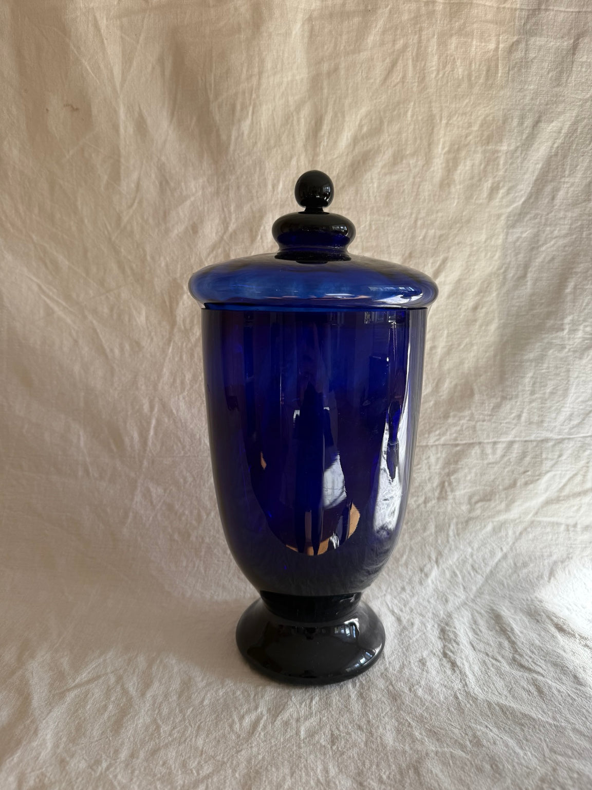 Vintage cobalt blue glass decorative lidded urn on linen backdrop