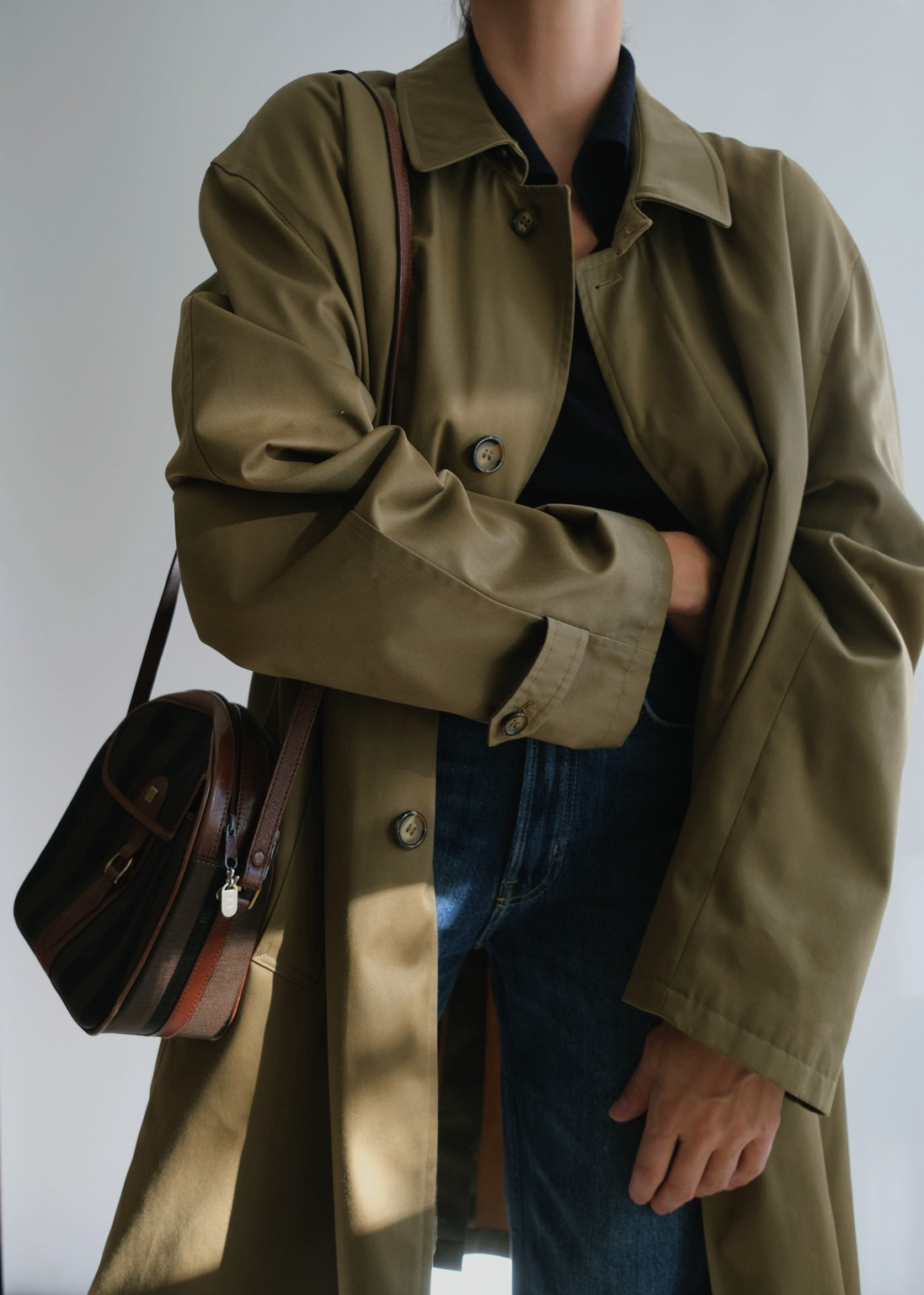 Vintage military green oversized raincoat styled with denim and vintage shoulder bag